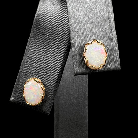 A pair of Australian white opal stud earrings in yellow gold shown close-up on a ring display.