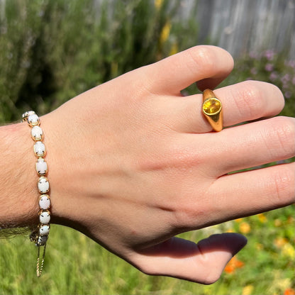 Hand wearing gold ring with an Australian white opal tennis bracelet around wrist in natural light.