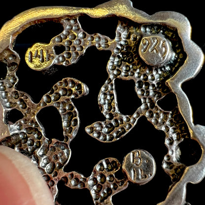 Close-up of the back of a silver pendant with the hallmarks "14k", "925", and "B. IL."