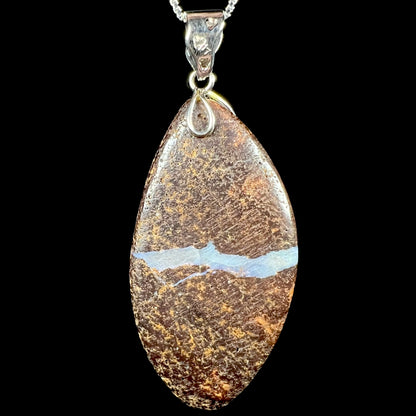 Back side of an Australian boulder opal pendant shown close-up against a black background.