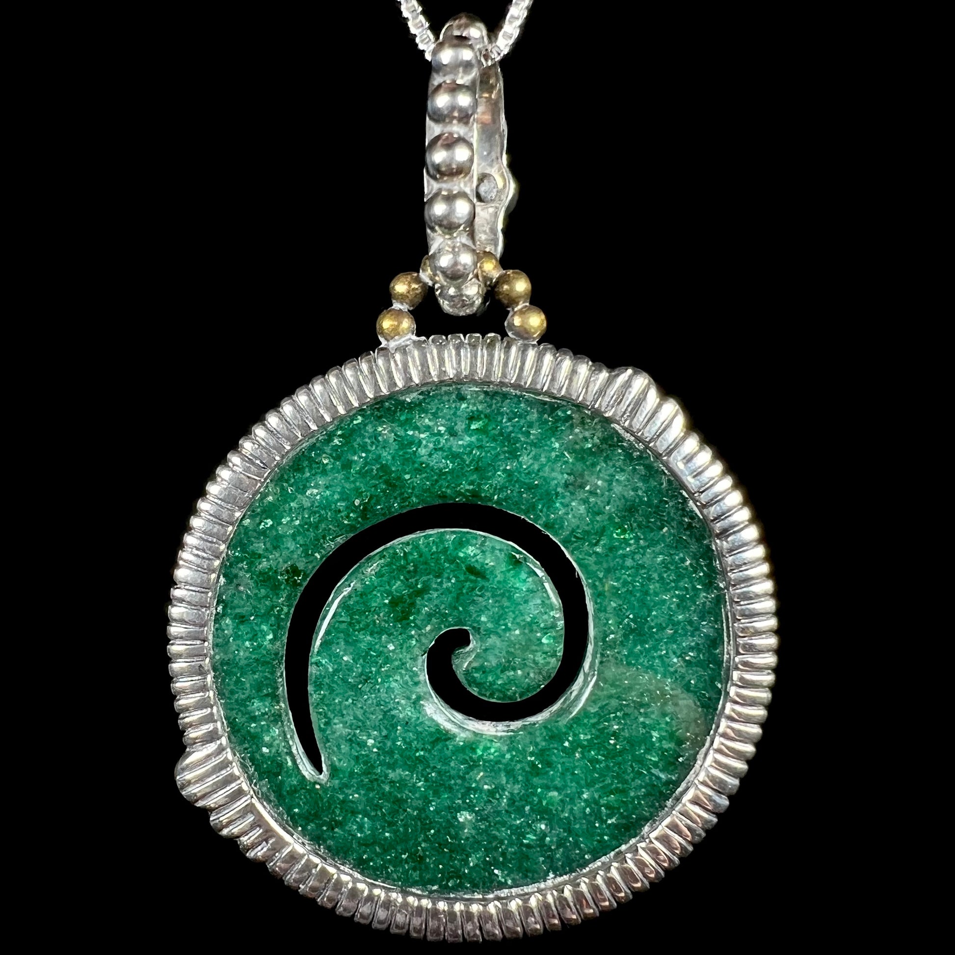 Back side of a carved green aventurine koru spiral necklace in a sterling silver and bronze setting.