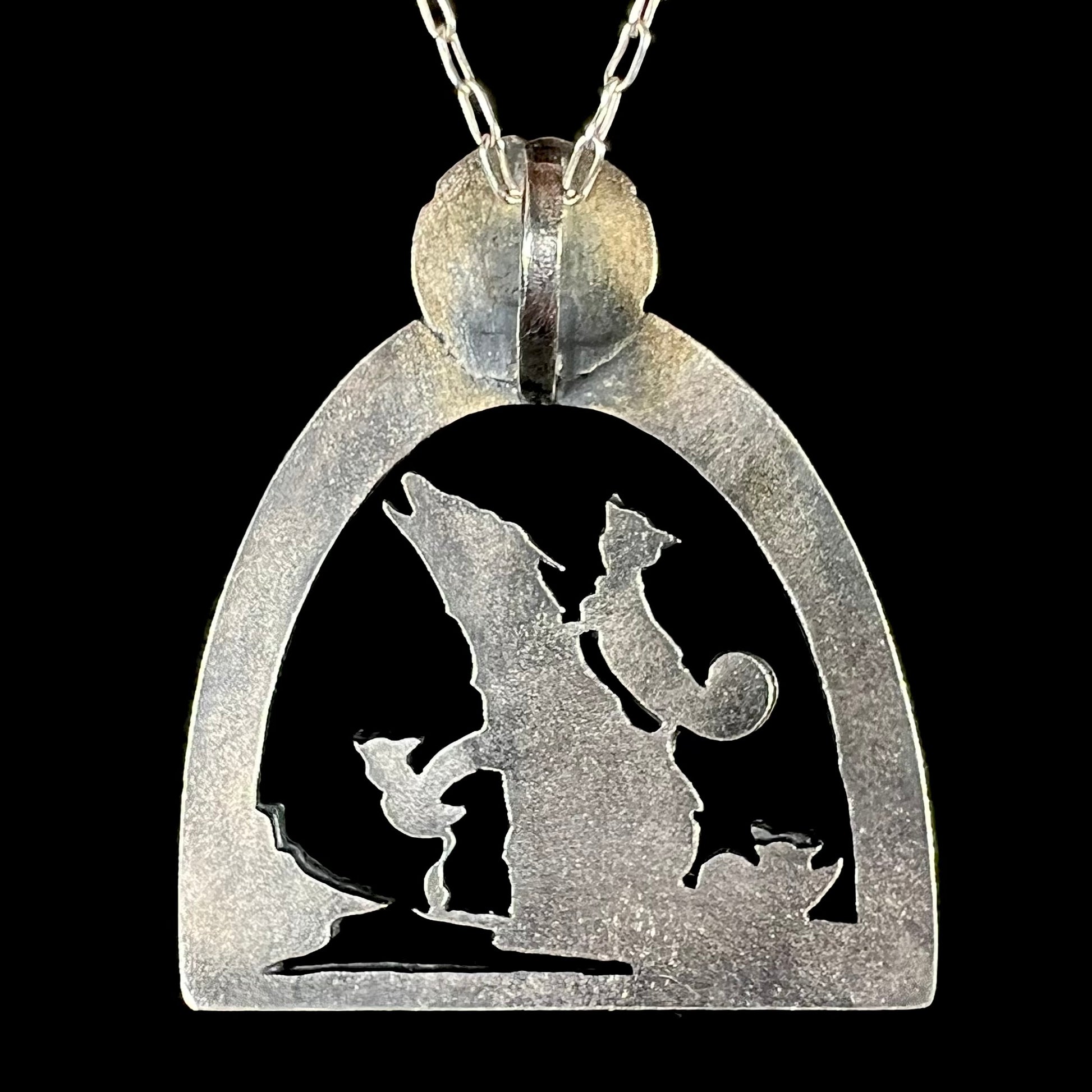 Back side of a handmade silver wolf and cat design necklace, shown against a black background.
