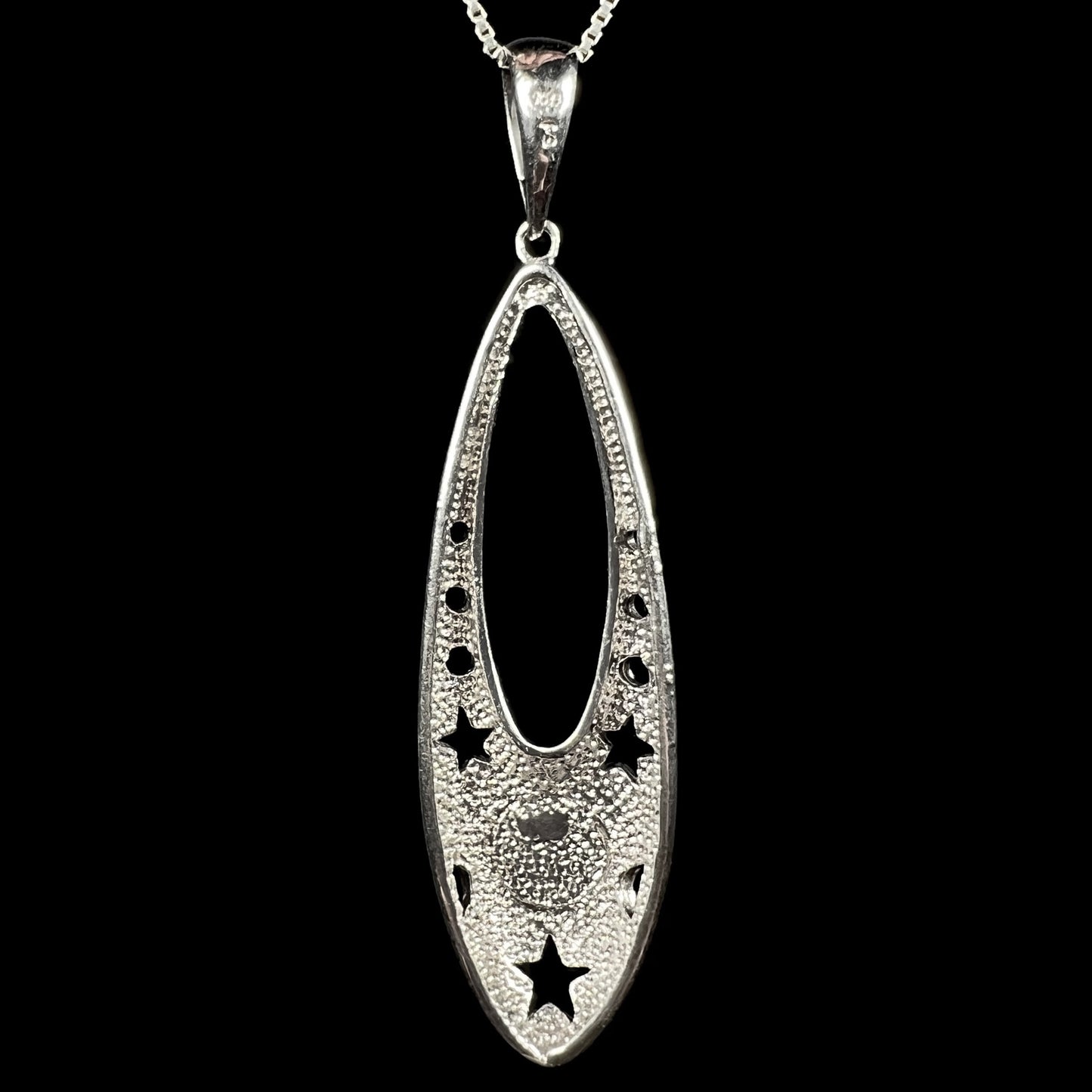 Back side of a sterling silver ballerina shoe pendant, shown against a black background.
