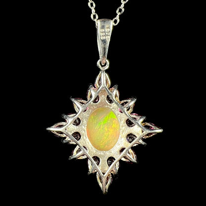 Back side of a sterling silver Ethiopian opal and garnet pendant, shown on a chain against a black background.