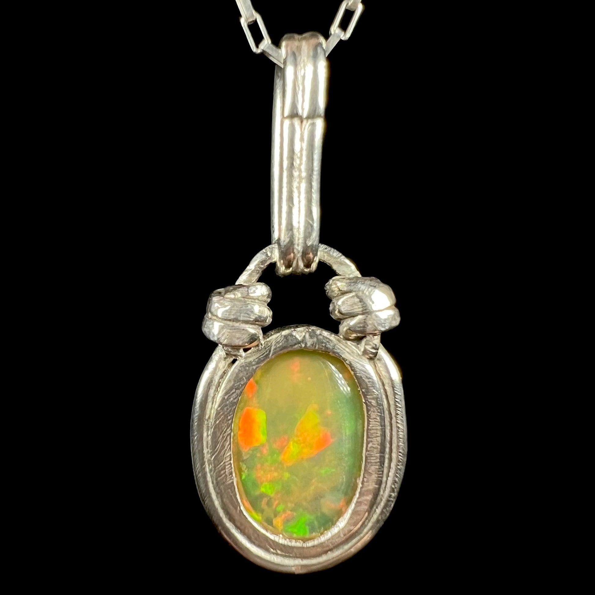 The back side of a colorful sterling silver Ethiopian opal pendant, shown against a black background.