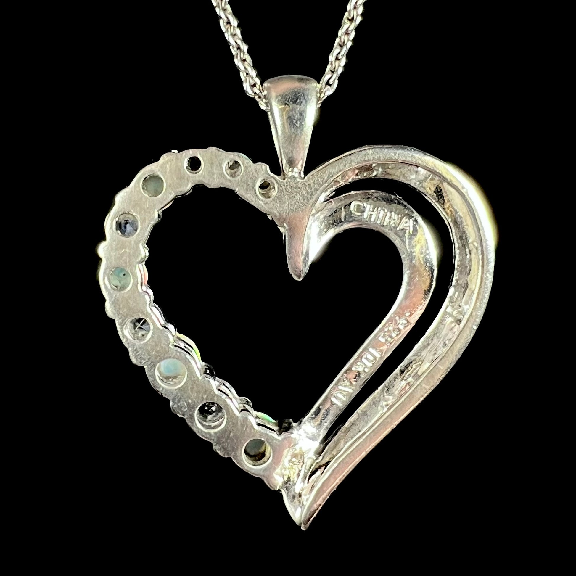 Back of a sterling silver heart pendant shown close up against a black background.