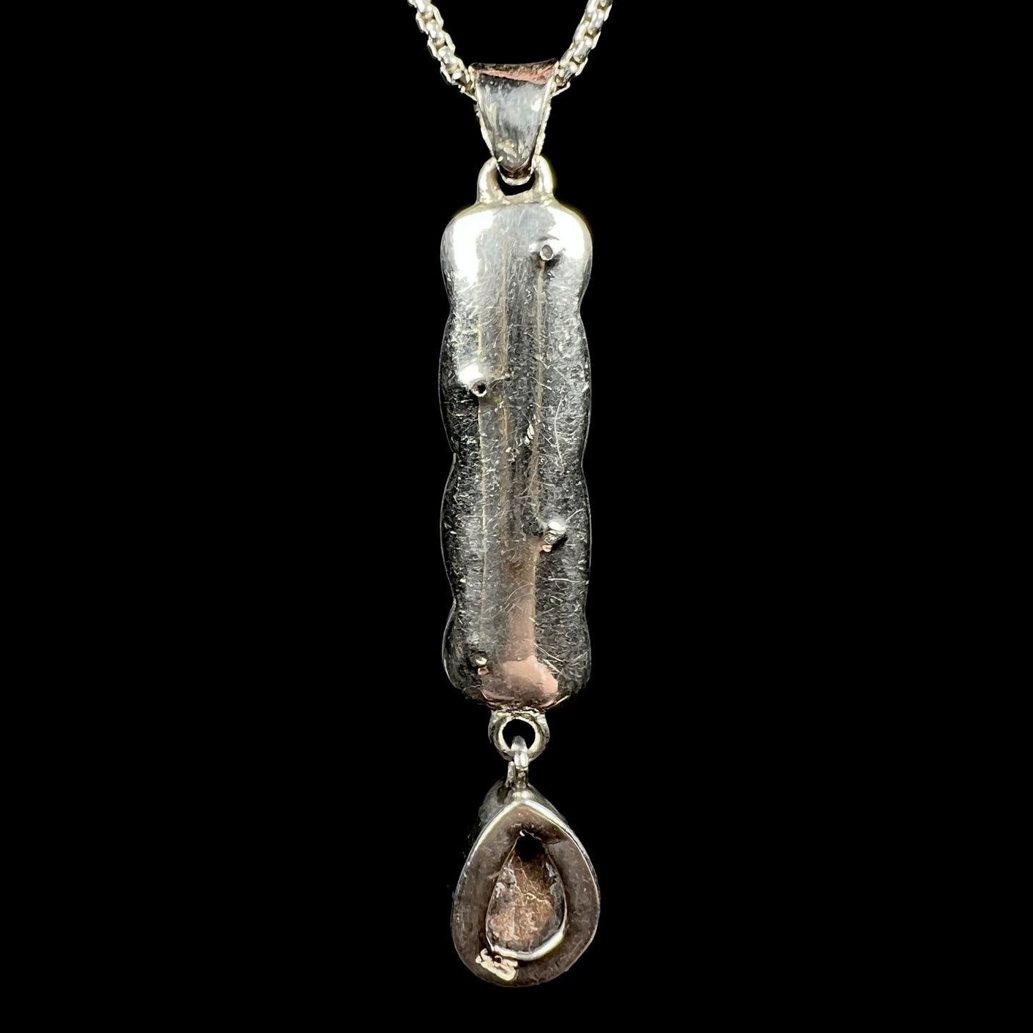 A sterling silver opal doublet drop pendant shown from the back side.  The opal is not visible; its ironstone backing and a "925" stamp are.