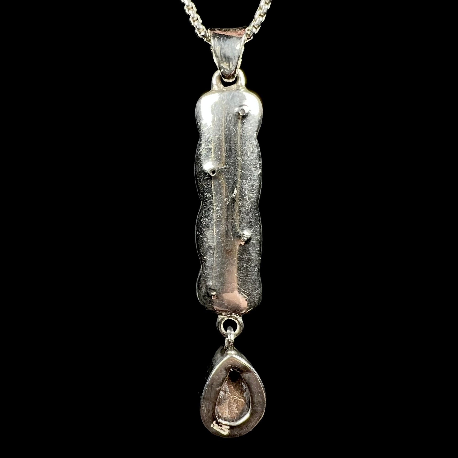 A sterling silver opal doublet drop pendant shown from the back side.  The opal is not visible; its ironstone backing and a "925" stamp are.