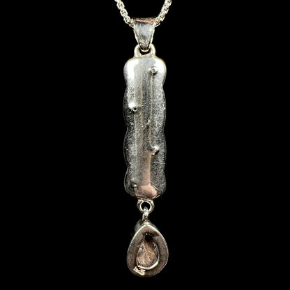 A sterling silver opal doublet drop pendant shown from the back side.  The opal is not visible; its ironstone backing and a "925" stamp are.