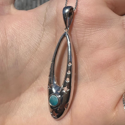 A sterling silver and opal doublet ballerina shoe necklace shown from an angle in a hand in the sunlight.