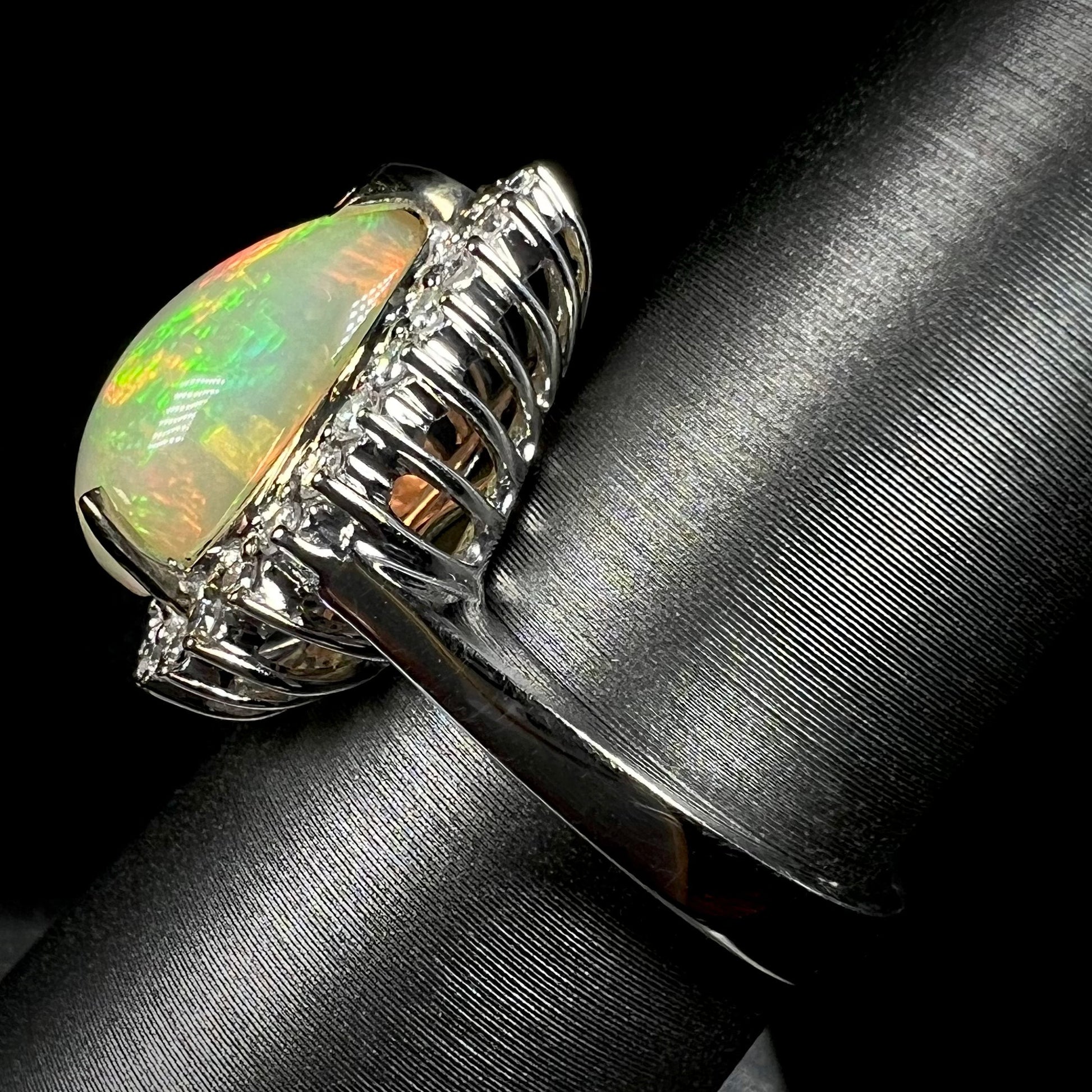 Side profile view of a basket set Ethiopian opal and diamond halo ring, focused on the ring's 18k white gold shank.