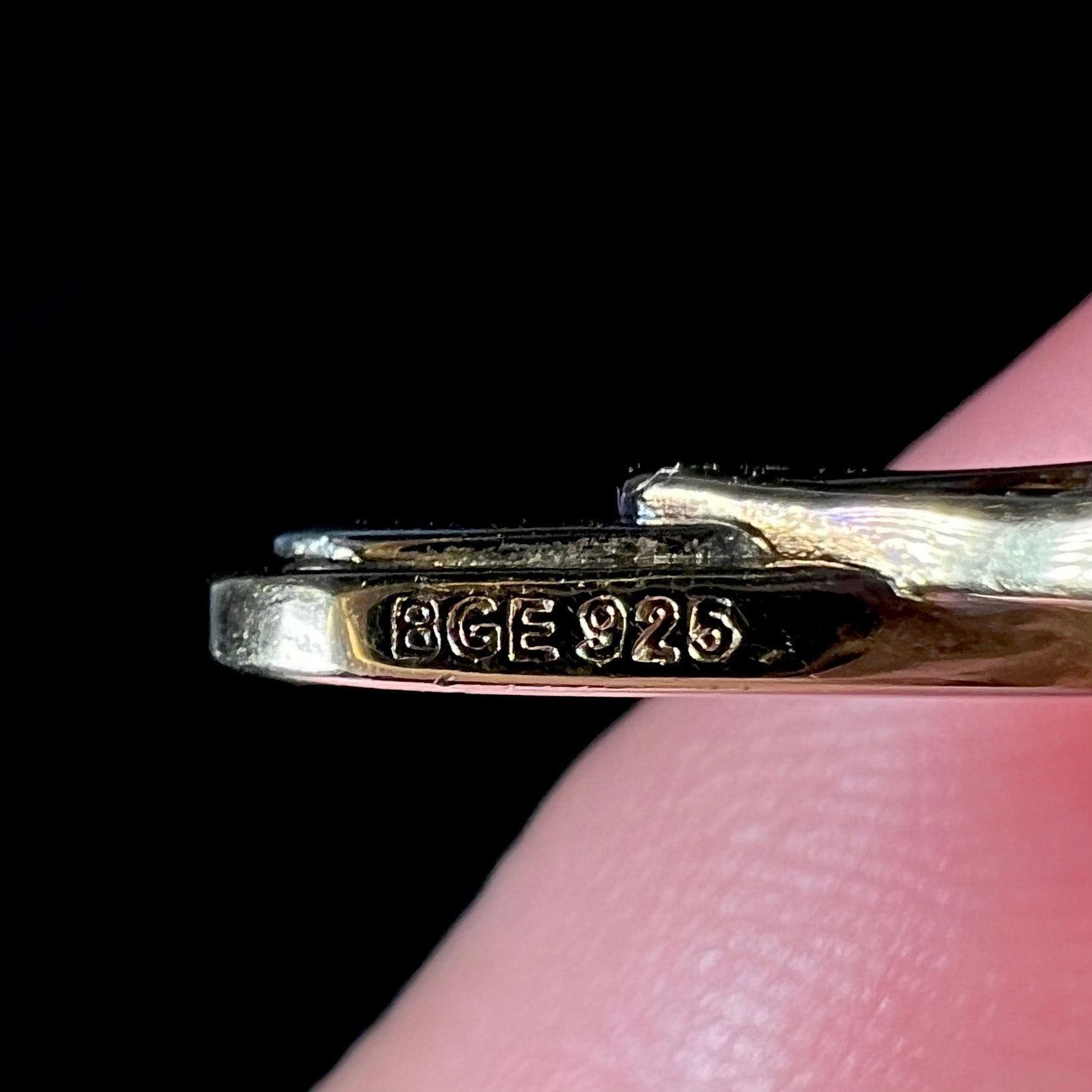 Close-up of a mother's cross hallmark stamp that reads "BGE 925".