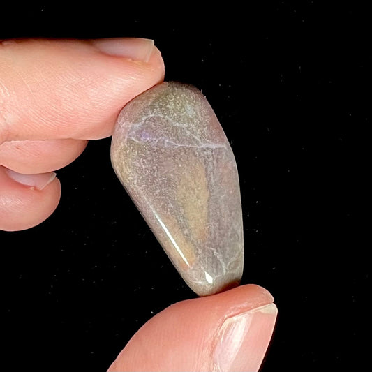 A tumbled turkiyenite purple jade stone.  The rock has a green tint from an epidote matrix.