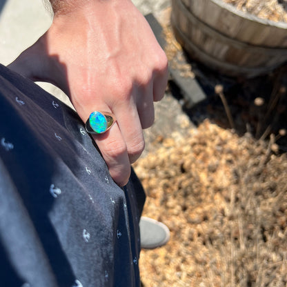 Hand resting on person's hip while wearing a big blue Australian opal men's ring in sunlight