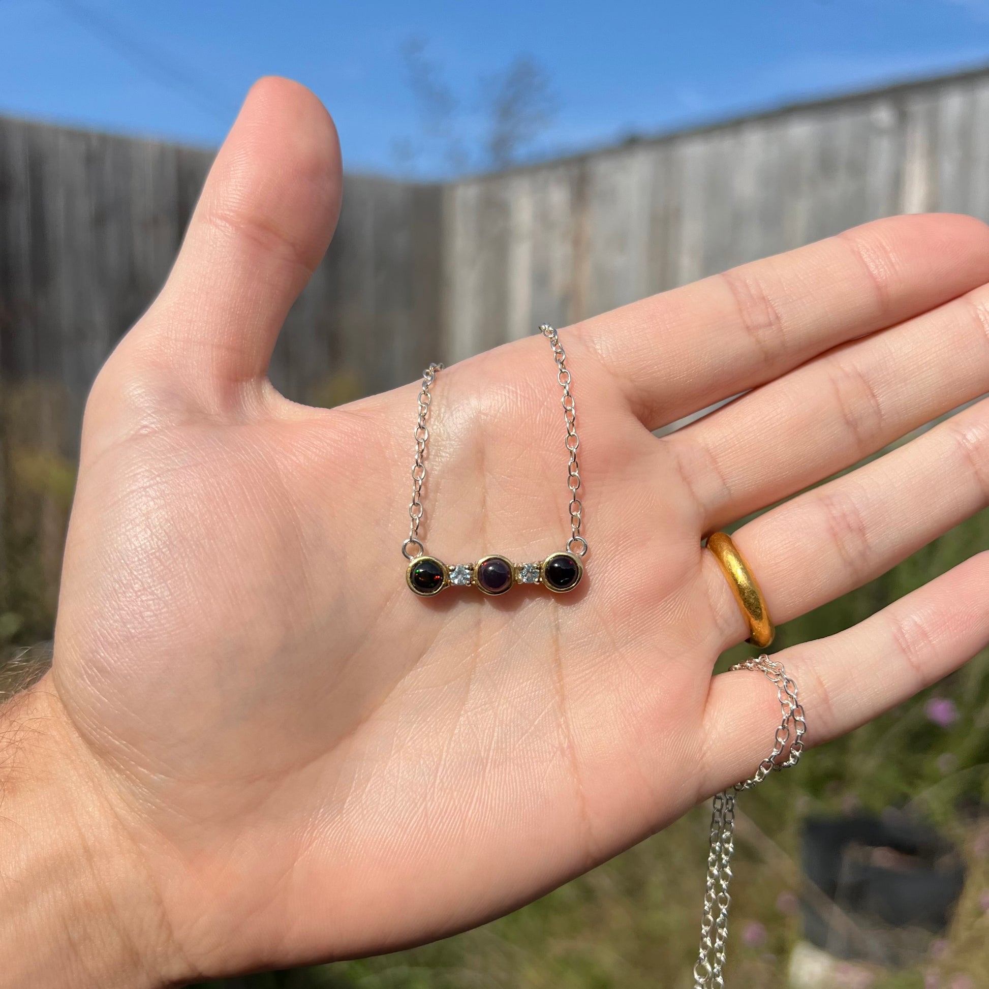 A three-stone black Ethiopian opal and white topaz necklace in two-tone sterling silver.