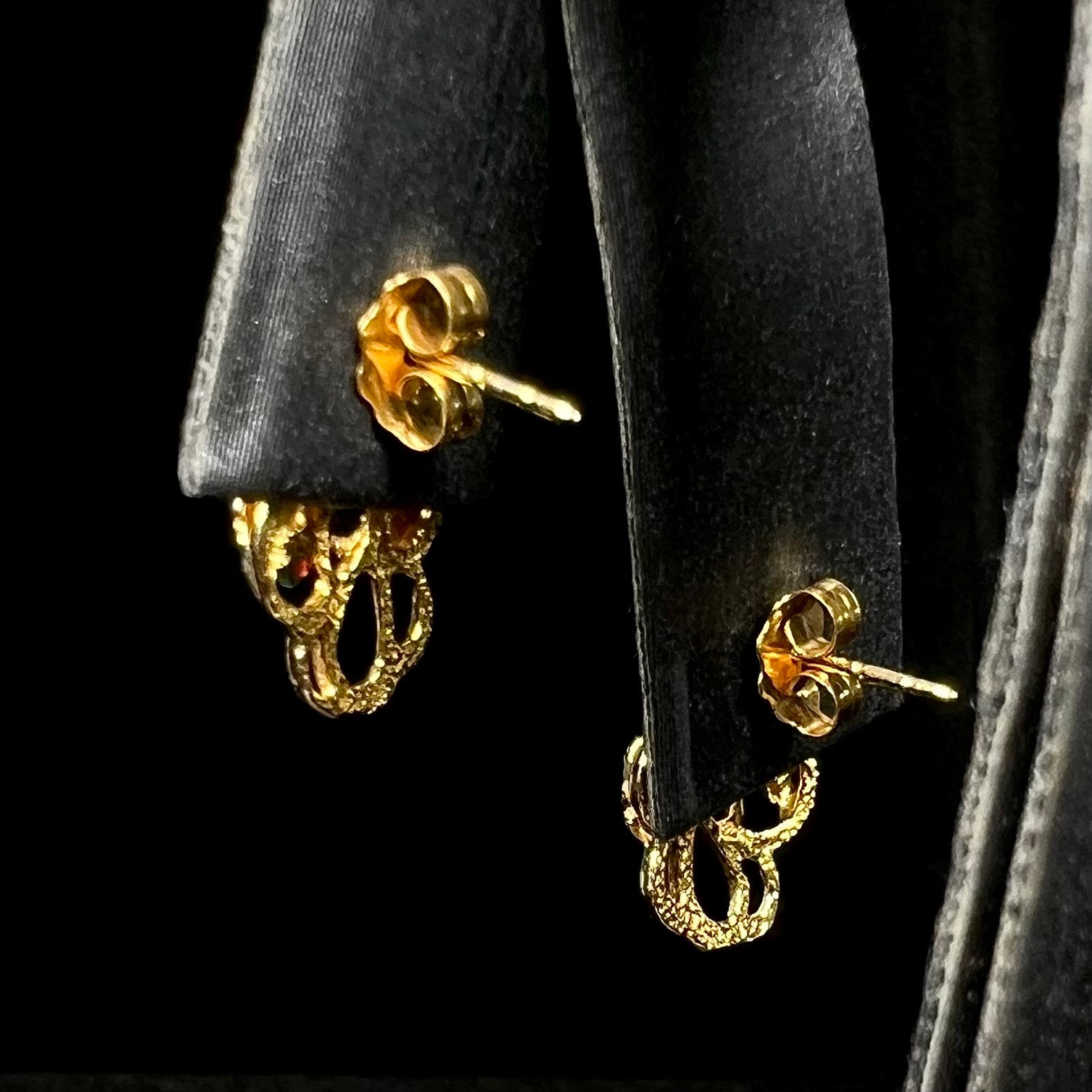 Back side of Black Hills gold earrings on display showing butterfly backs and posts
