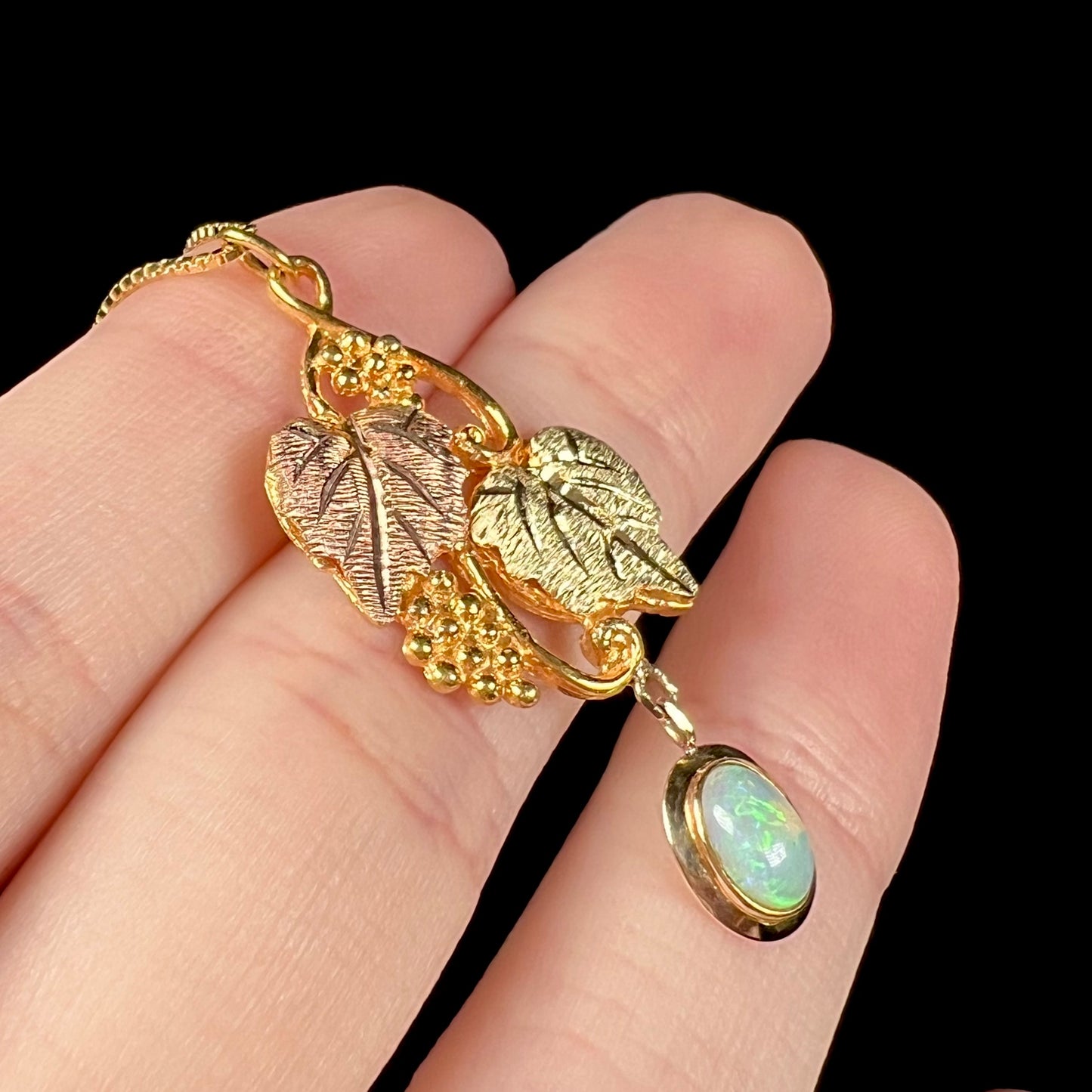 Angled macro view of a Black Hills gold opal necklace, showing green flashes of color in the opal.