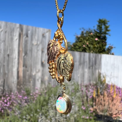 Angled view of a Black Hills gold opal necklace in sunlight, showing a mix of red and green flashes in the opal.