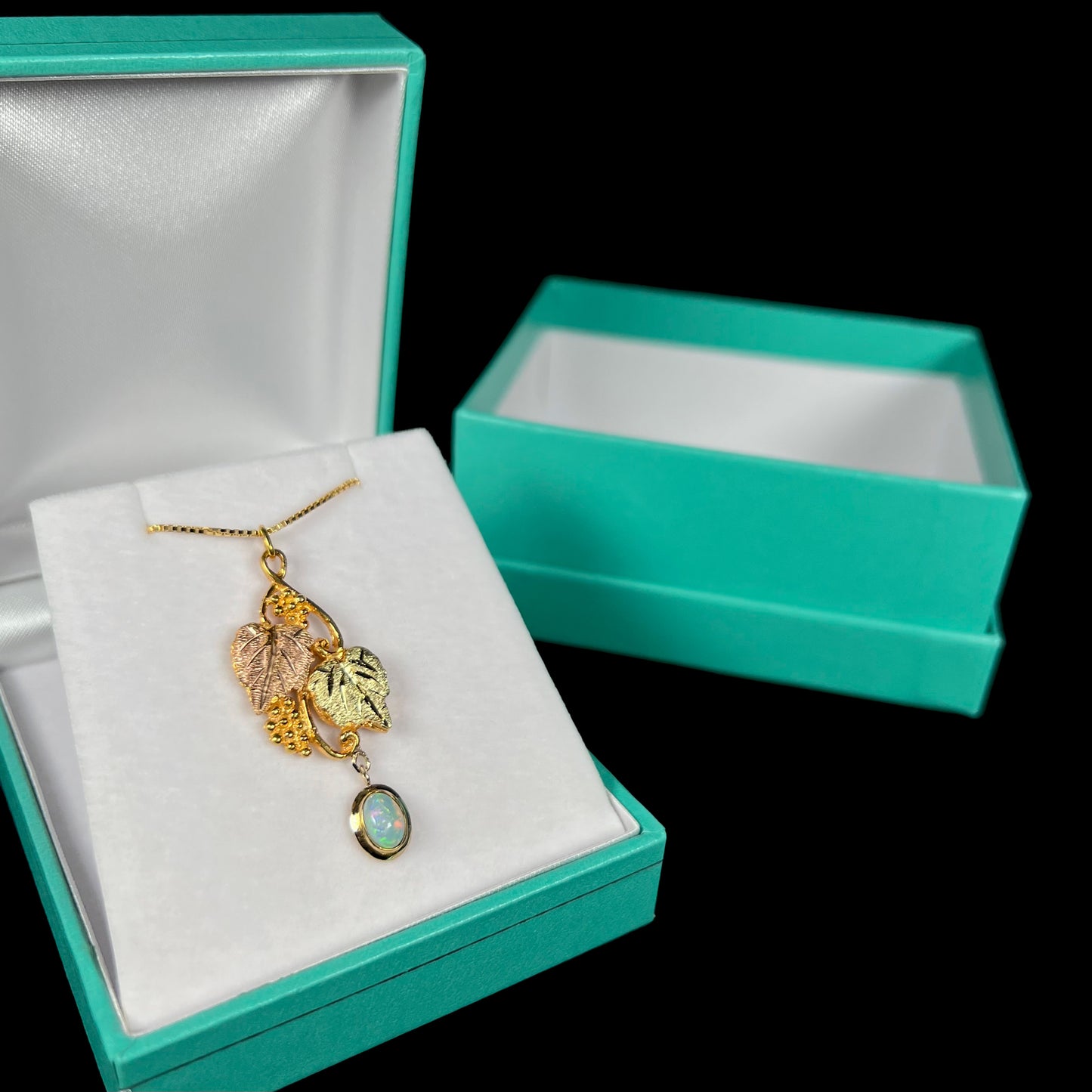 Vintage Black Hills gold opal necklace in a blue pendant box against a black background, featuring a unique customized design.