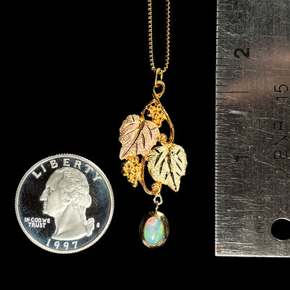 Black Hills gold opal necklace beside a quarter and ruler for scale, measuring approximately 1.75 inches long with visible red flash in the opal.