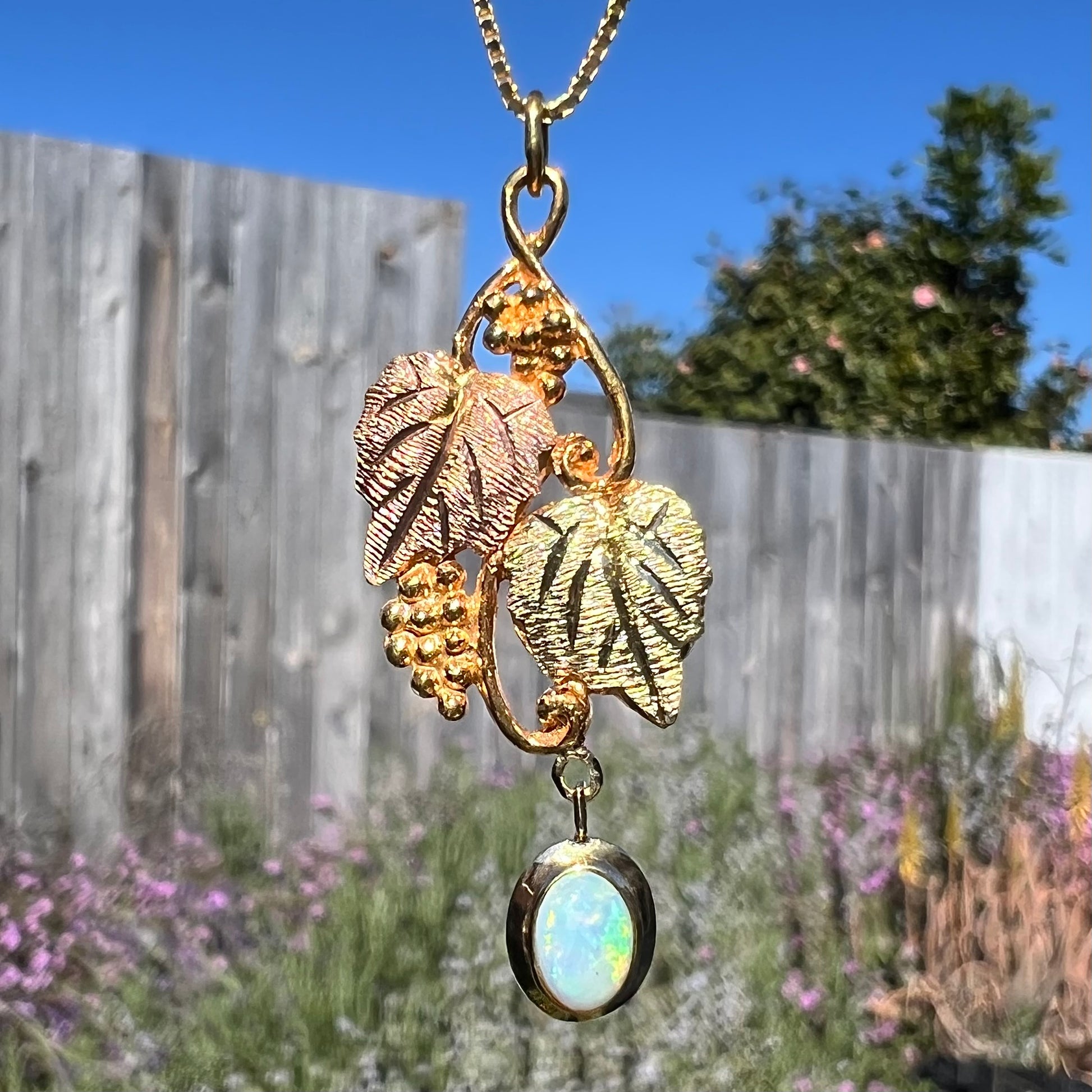 Macro view of a Black Hills gold opal necklace in natural sunlight, showing the opal’s glowing color play.