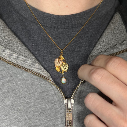 Black Hills gold opal necklace worn around the neck on a black t-shirt with a partially zipped sweatshirt, showing red flashes in the opal.