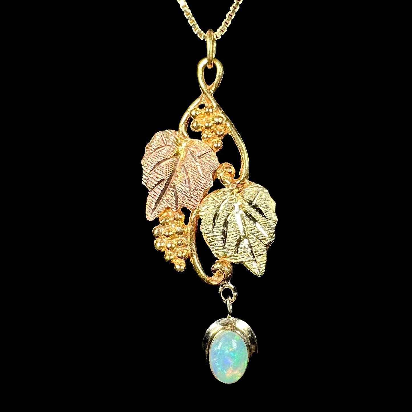 A vintage Black Hills gold opal pendant against a black background, showing a faint blue color in the opal.