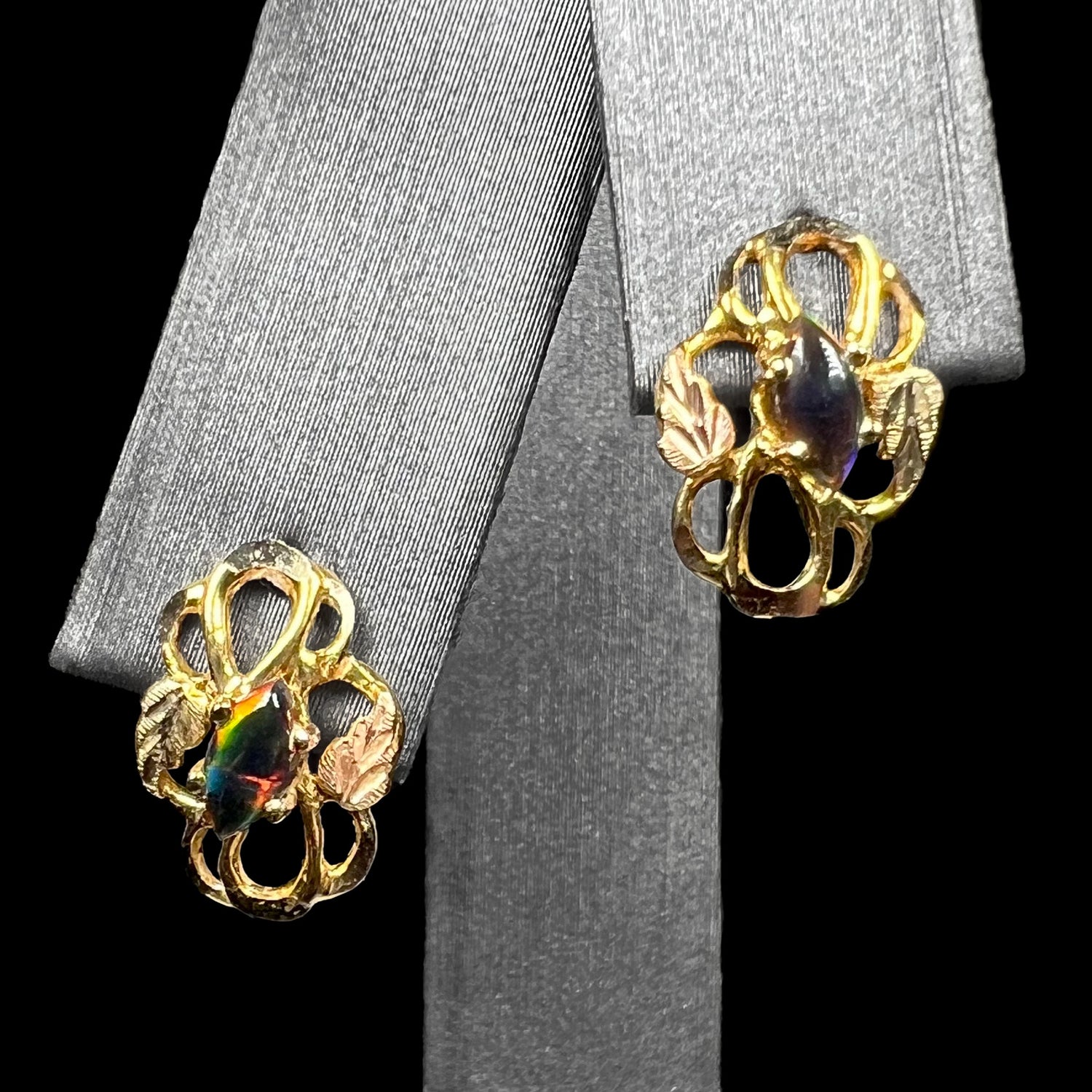 Pair of lab-created black opal black hills gold stud earrings on earring display