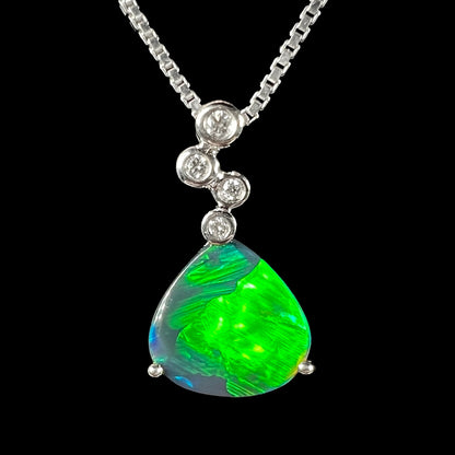 An 18k white gold black opal and diamond necklace displayed against a black background, featuring a bright green flash.