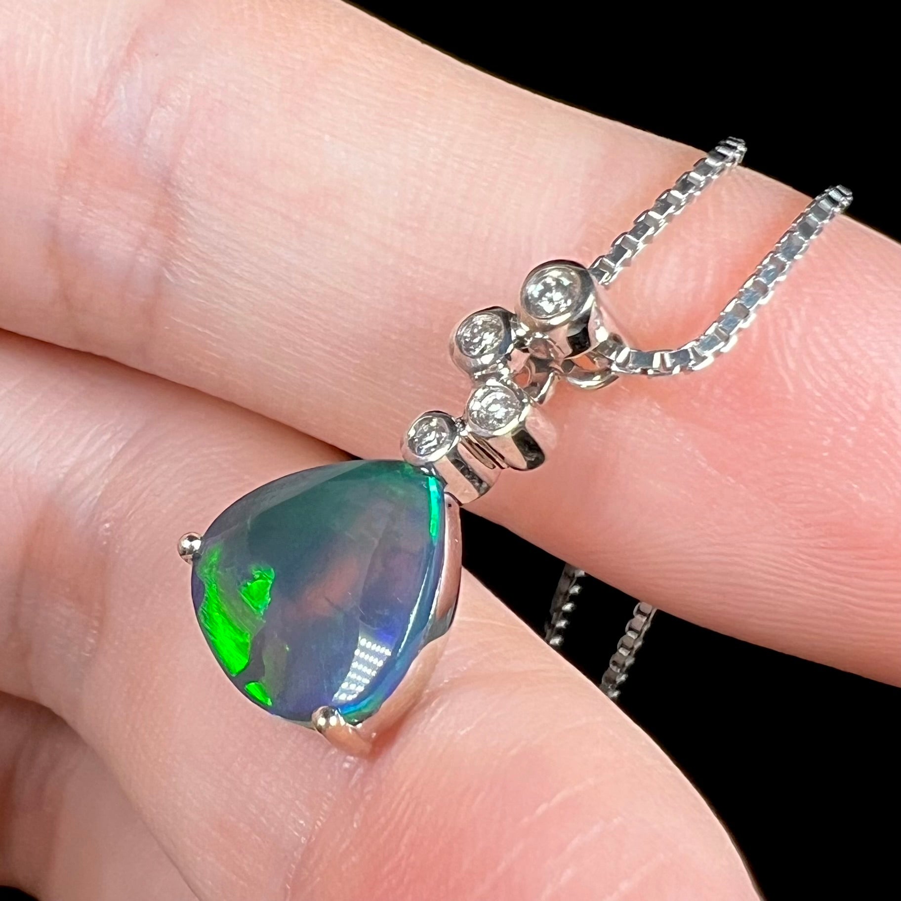 A side view of a black opal diamond necklace, where a small green flash is visible.