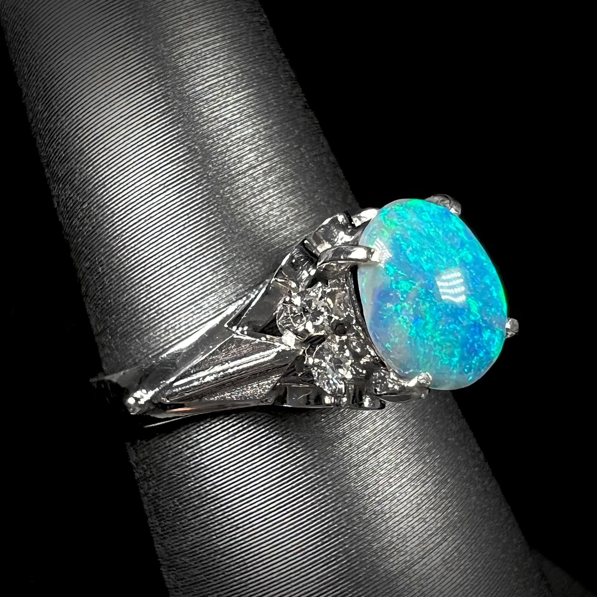 A macro photo of a black 0.89ct black opal and diamond ring.  The ring is dainty and delicate.