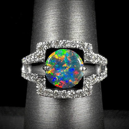 A round Lightning Ridge black opal engagement ring with intense red multicolor fire, set in 14k white gold with diamonds by Luciano Bortone.  Studio lightning enhances clarity.