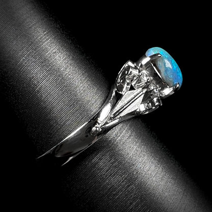 A side view of a platinum black opal engagement ring.  The opal shows blue colors and dark matrix.