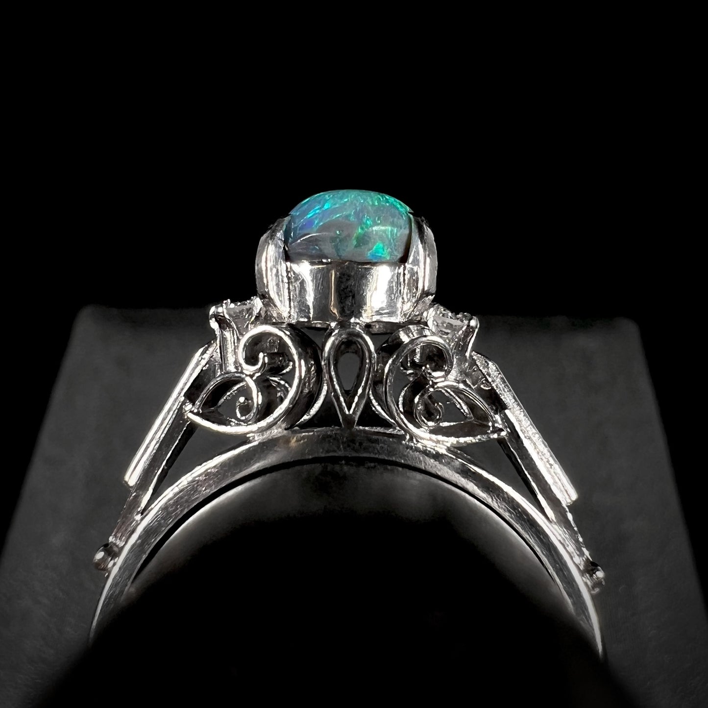 The gallery view of a platinum black opal and diamond ring, showcasing the ring's intricate filigree design.