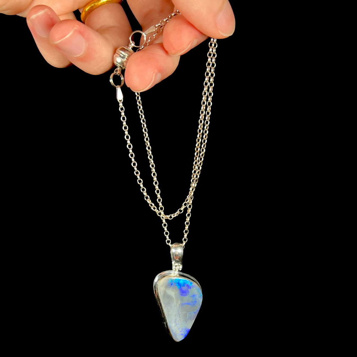 Black opal necklace with blue flashes of color dangled by hand from sterling silver chain.  Chain has magnetic clasp