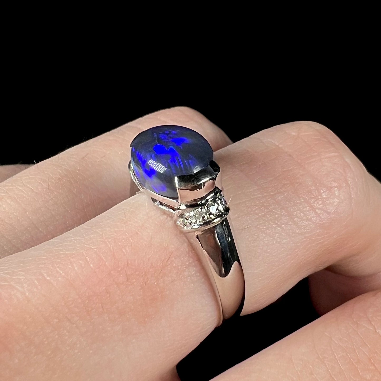 A Lightning Ridge black opal platinum ring worn on a finger.