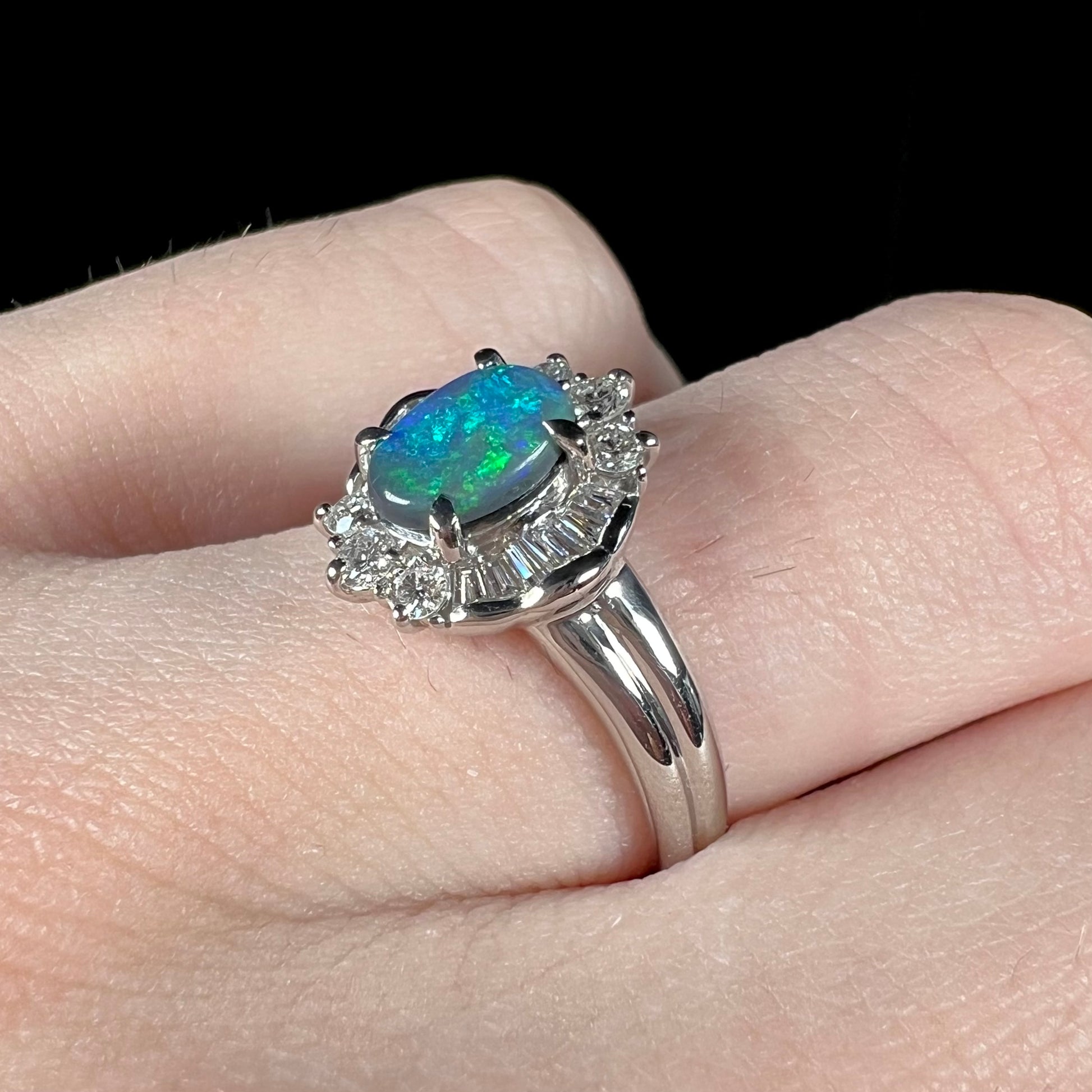 Macro closeup of platinum black opal engagement ring, showing diamond halo and blue color play in the opal.