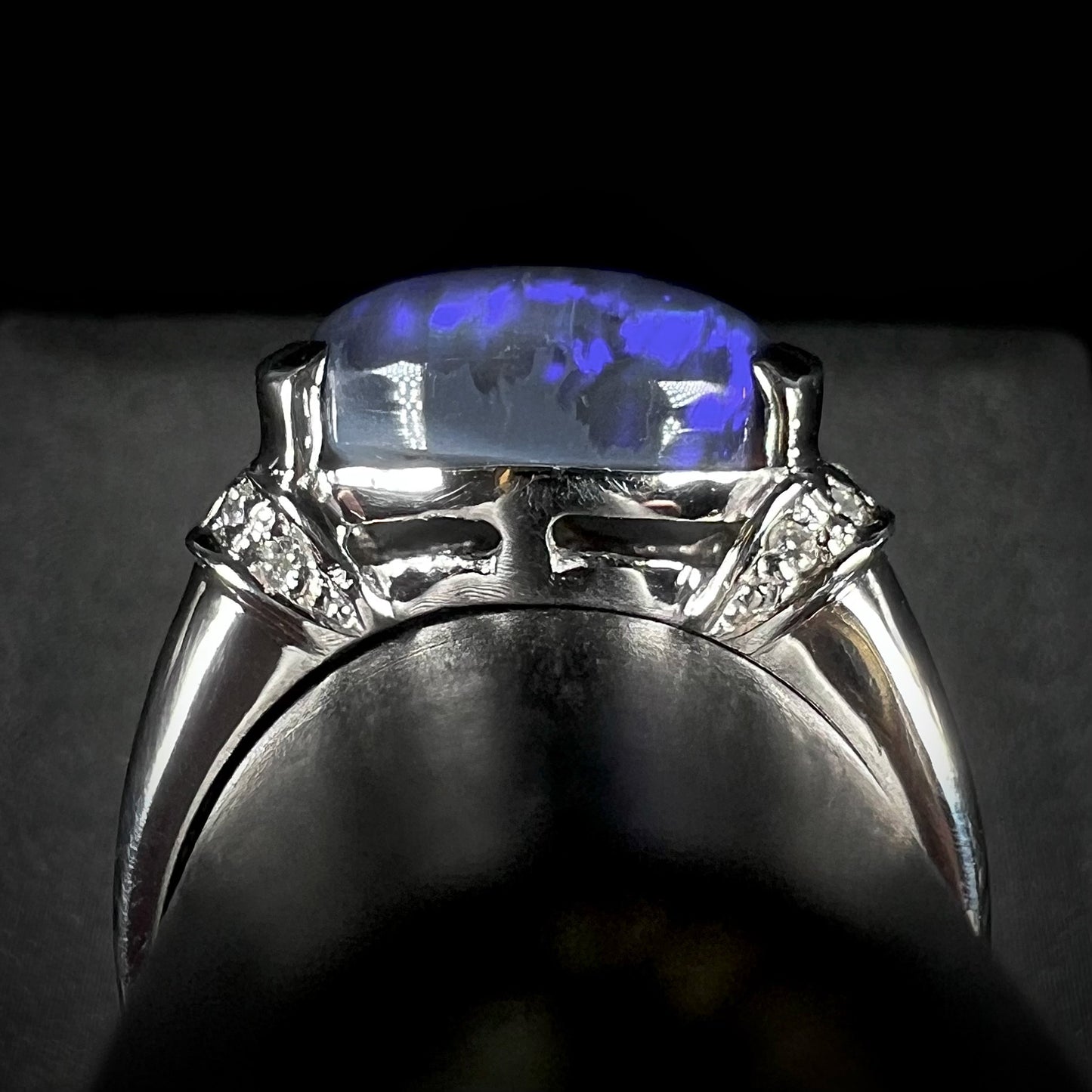 The gallery view of a platinum black opal ring.  The opal is set in a half-bezel, and its edges are exposed.