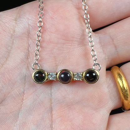 A three-stone black Ethiopian opal and white topaz necklace in two-tone sterling silver.