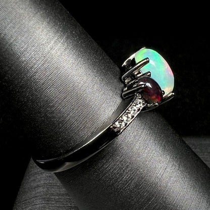 Black rhodium plated sterling silver opal ring with CZ accents on display, shown from side view