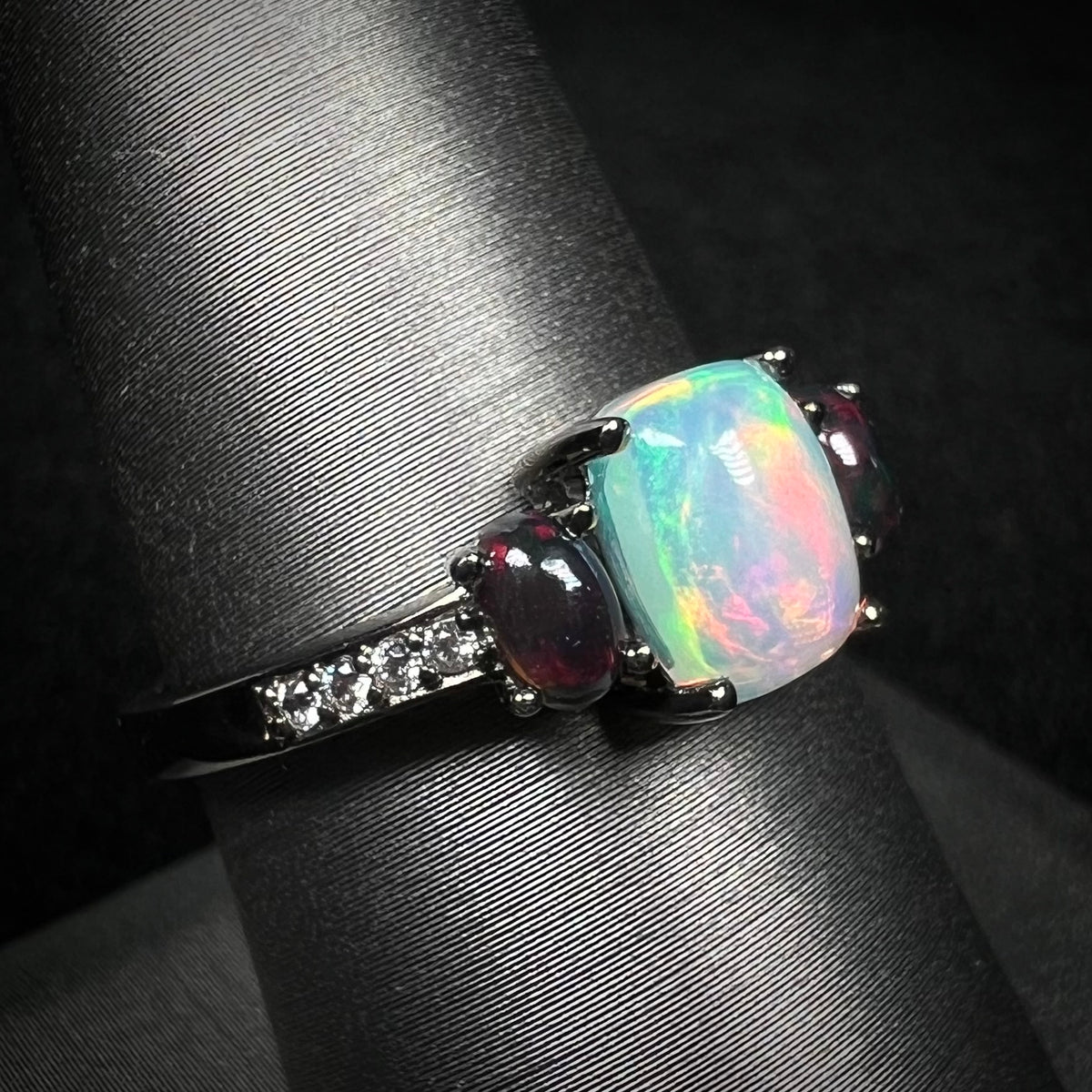 Ethiopian opal and CZ ring with black rhodium plated sterling silver finish on display