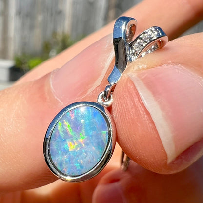 An oval cut black opal doublet necklace set in sterling silver with white zircon accent stones.