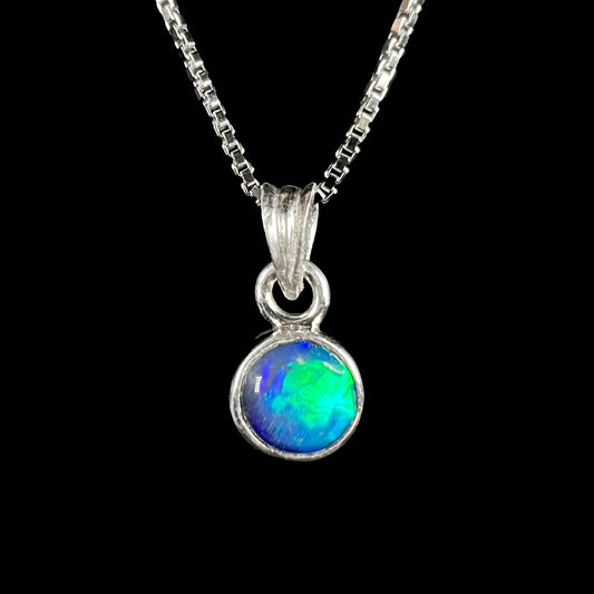 A sterling silver, round cabochon cut black opal solitaire necklace.  The opal has green and blue fire.