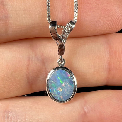 A sterling silver necklace set with a natural black opal doublet and white zircon accent stones.