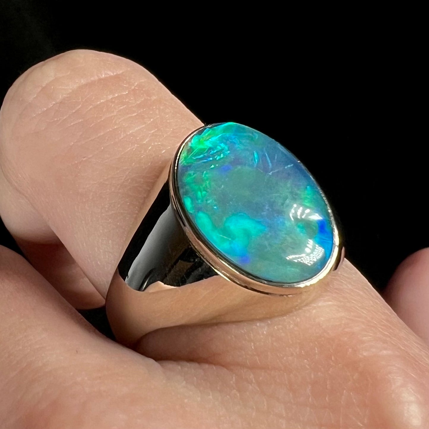 14k white gold blue Australian opal men's ring shown close-up on finger