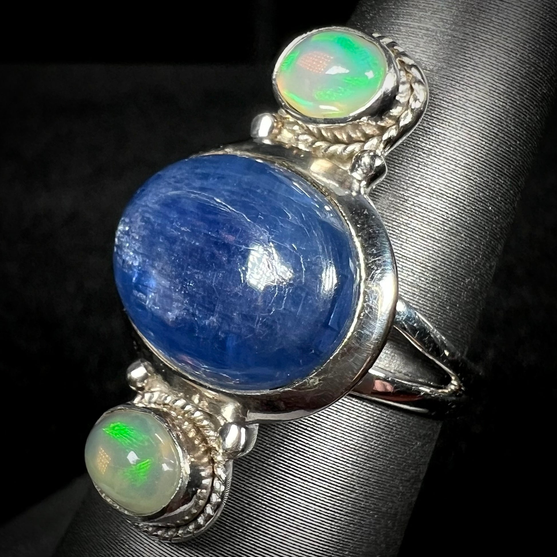 Angled view of a blue kyanite and Ethiopian opal ring in sterling silver against dark background.