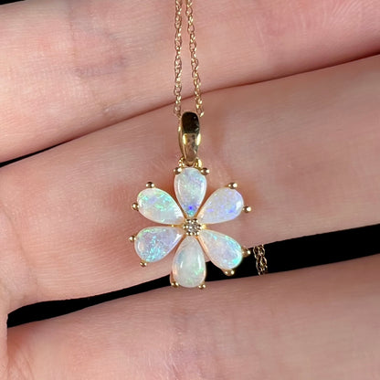 Delicate blue flashes visible in opal flower pendant, held in hand