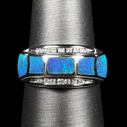 Close-up of 14k white gold ring inlaid with five blue Australian opals, accented by two channels of diamonds, shown on ring display