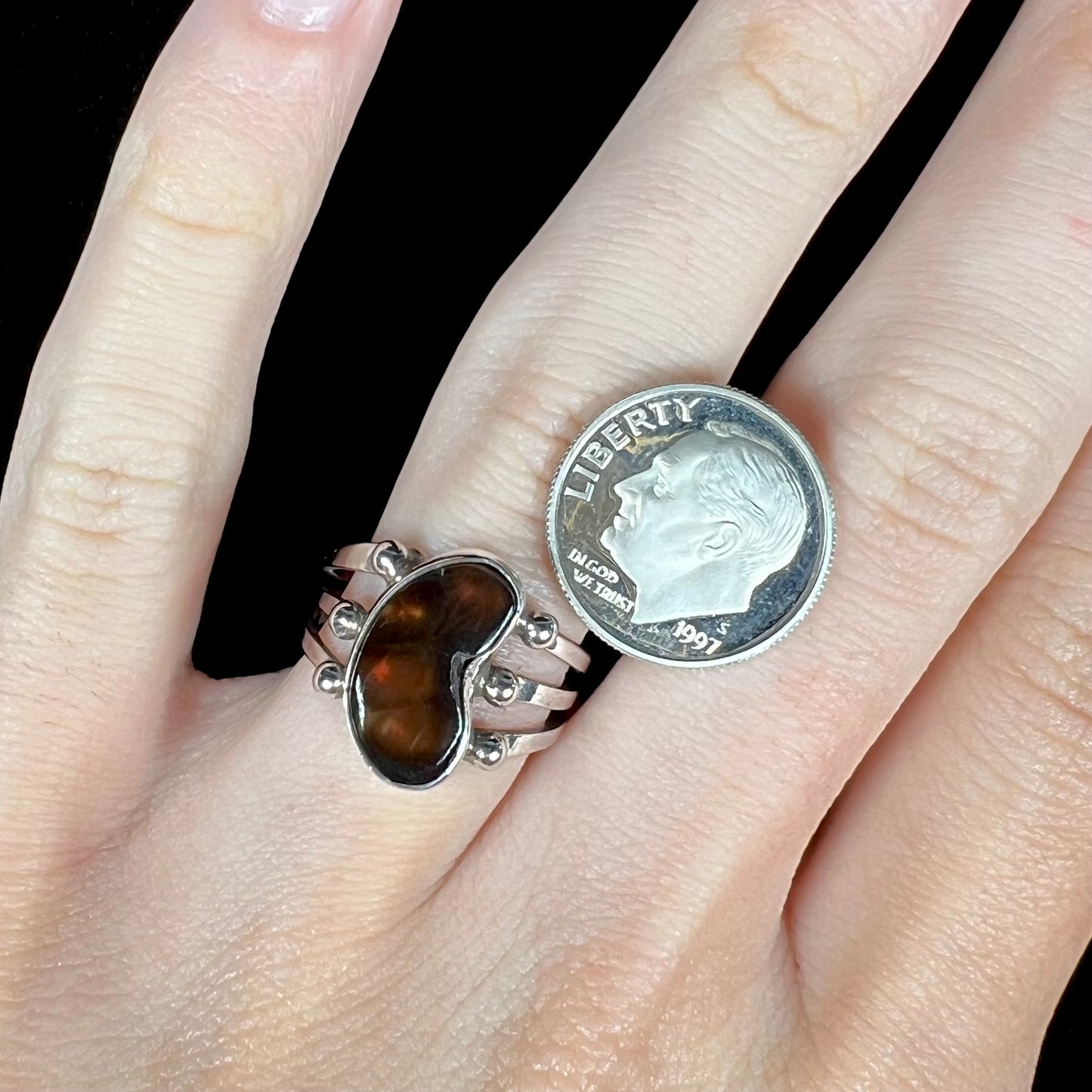 Fire agate ring on hand with a dime for scale reference.
