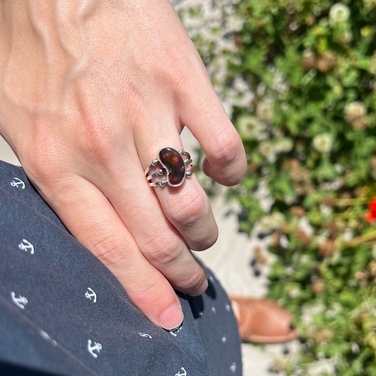 Lifestyle photo of fire agate ring worn on hip in natural sunlight.